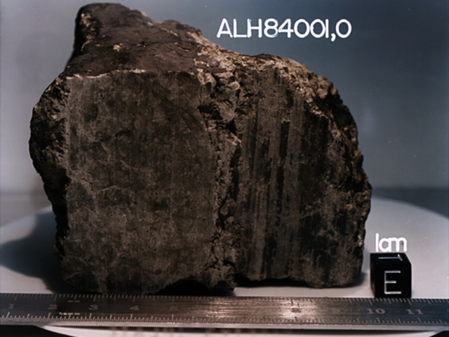 17. Метеорит АLH84001 Под этим именем скрывается, пожалуй, самый известный из 34 марсианских метеоритов, найденных на Земле. Его обнаружили 27 декабря 1984 года в горах Алан Хиллс в Антарктиде. Согласно проведенным исследованиям, возраст инопланетного тела составляет от 3,9 до 4,5 миллиардов лет. Метеорит, вес которого равен 1,93 кг, упал на Землю около 13 тыс. лет назад. Существует гипотеза, согласно которой он откололся от поверхности Марса во время столкновения планеты с крупным космическим телом. 