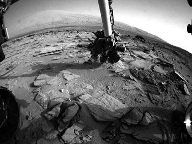 Роботизированная "рука" марсохода изучает горную породу и марсианский грунт, 3 июля 2013 года.